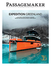 A magazine cover for Passagemaker featuring the bold headline "EXPEDITION GREENLAND." The cover photo showcases a striking, bright orange long-range expedition trawler navigating vibrant turquoise water dotted with small chunks of floating ice. In the background, a steep, dark rocky mountain rises into low-hanging fog and dense grey clouds. Subtext below the headline reads, "A FAR NORTH CRUISE REVEALS ICEBERGS, SEVERE WEATHER AND NATURE'S STARK BEAUTY." A golden 30th-anniversary logo is displayed in the bottom right corner, just above the issue date "JULY/AUGUST 2026".