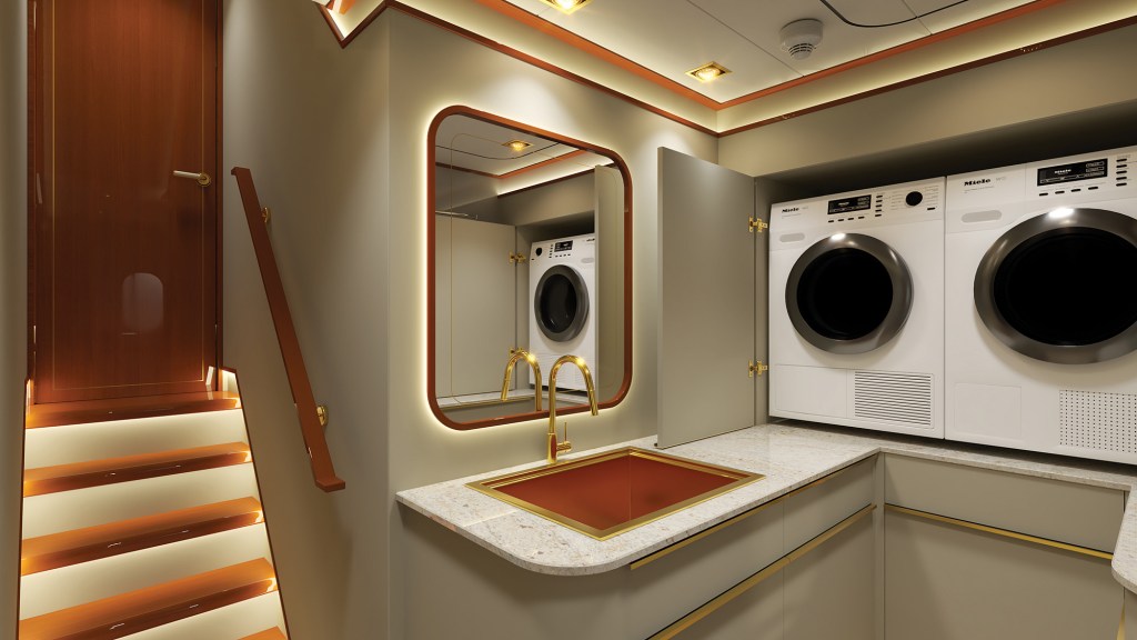 An interior rendering of a dedicated laundry and utility room on a modern yacht. On the right, a premium white Miele washer and dryer unit are neatly built into the grey cabinetry. A light-colored granite countertop features a unique, rectangular copper-toned sink fitted with a minimalist gold faucet. Mounted on the wall above the sink is a large, rounded-corner mirror with warm, integrated backlighting that reflects the appliances. On the left, a short flight of wood-paneled stairs with illuminated steps and a wooden handrail leads upward to a closed wooden door.
