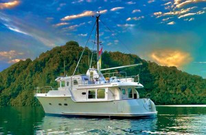 feat_Nordhavn 43 Celt A white Nordhavn 43 expedition yacht anchored in calm water near a lush green island with a dramatic, vibrant sky filled with glowing clouds overhead.