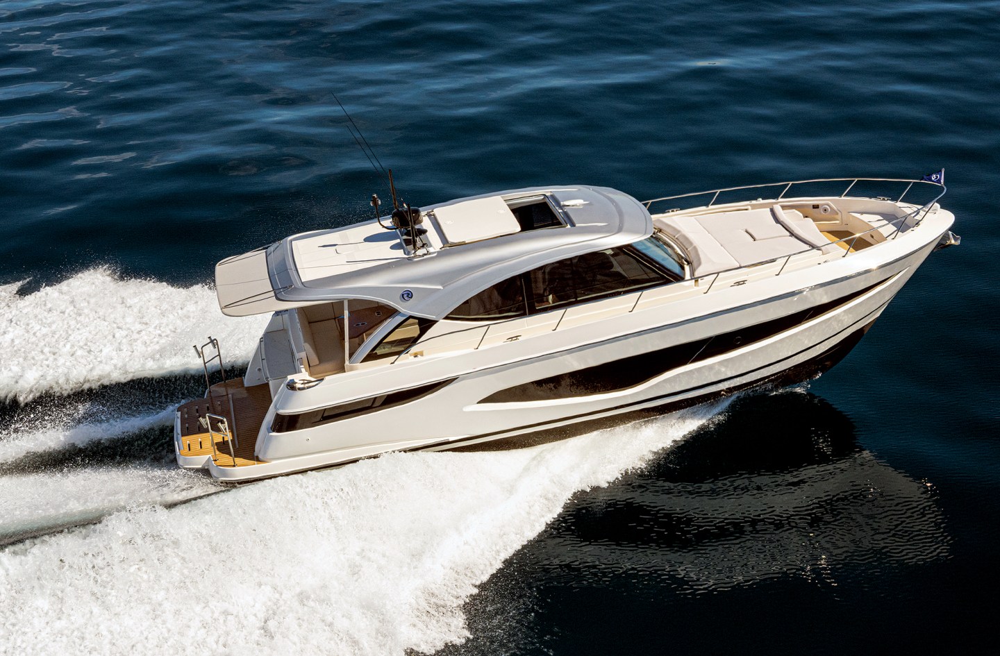A white Riviera 4300 Sports Express luxury motor yacht cruising at speed across deep blue ocean waters.