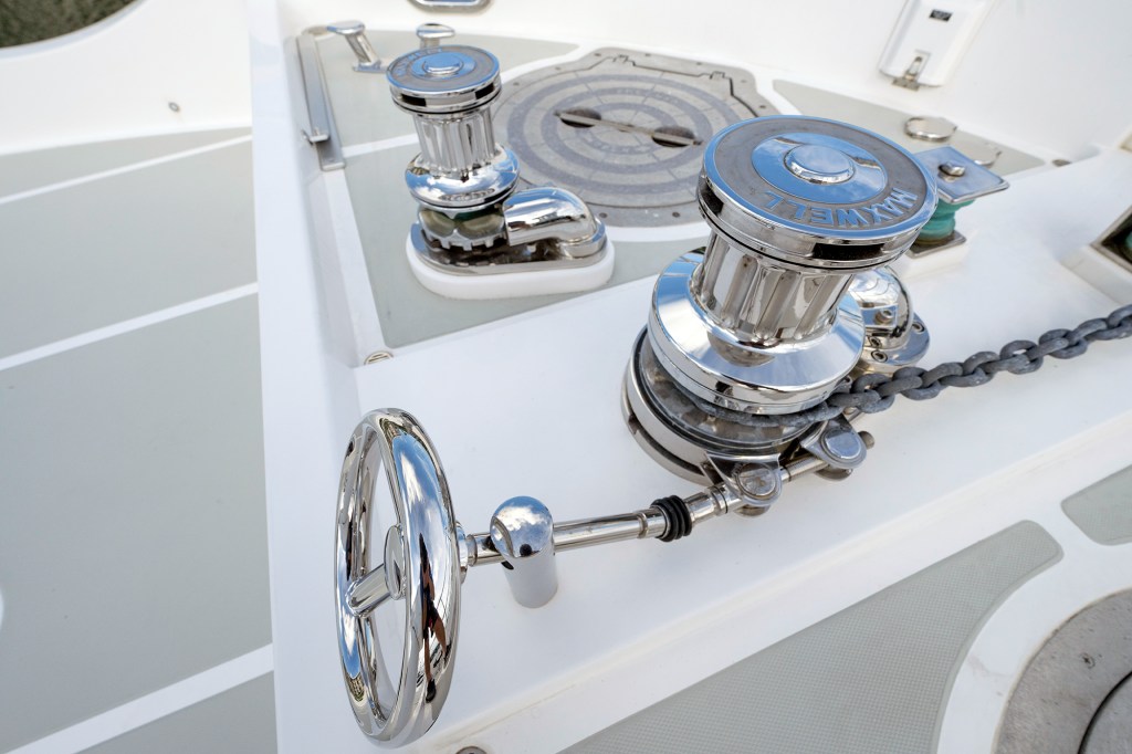 High-angle shot of a chrome Maxwell vertical windlass with an anchor chain fed through the gypsy on a white boat deck.