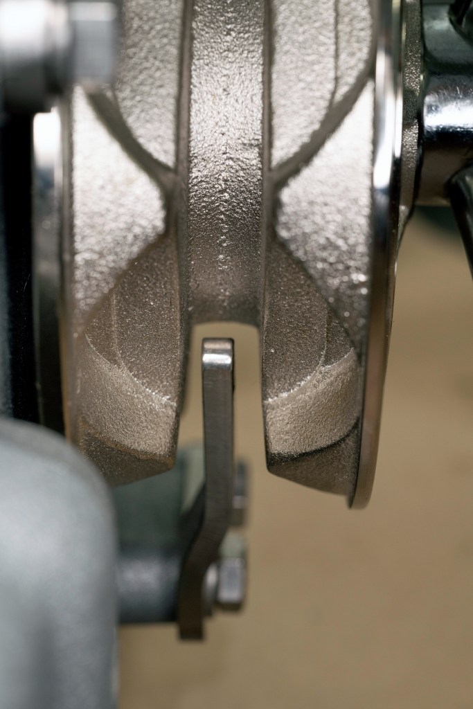 Macro shot of a windlass chain wheel gypsy showing the metal stripper finger positioned within the central groove.