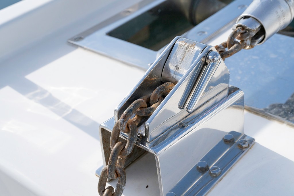 Stainless-steel deck-mounted chain stopper engaged over a galvanized anchor chain to take strain off the windlass.