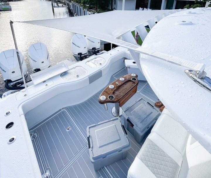 Custom boat sunshade canopy extended over the aft cockpit of a center console fishing boat supported by stainless steel poles.