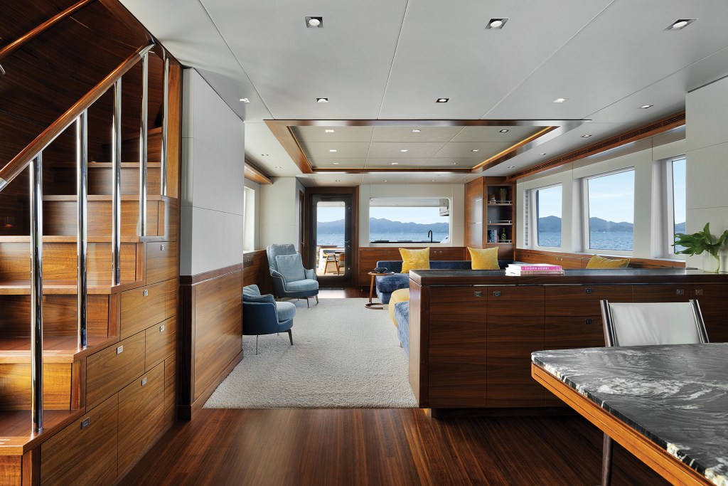 Spacious main salon interior of the Nordhavn 100 featuring rich teak woodwork, plush seating, and ocean views.