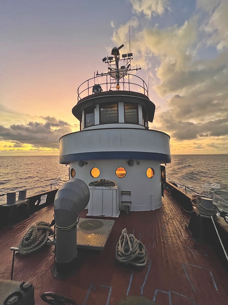 View from the wooden deck of the historic Robert Gray ship looking toward the pilothouse at sunset.
