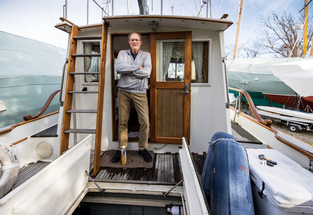 Photographer Onne van der Wal standing with arms crossed in the cockpit doorway of his restored Grand Banks trawler yacht.