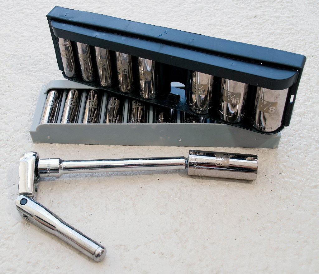 Socket set in plastic organizer holder alongside a flex-head ratchet handle and extension bar for boat engine repairs.