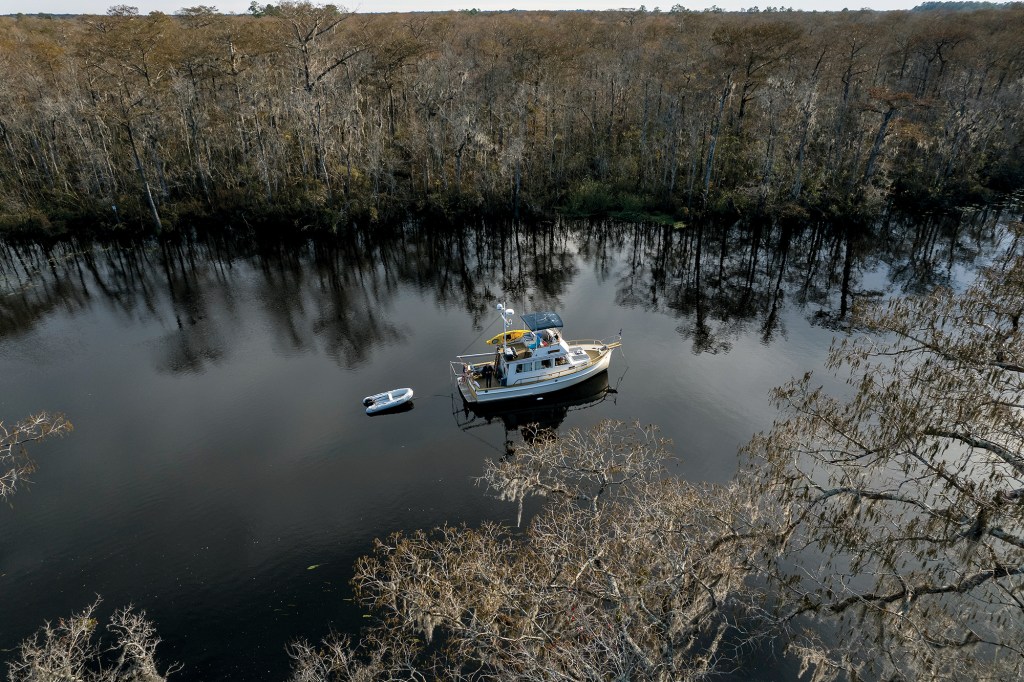 Aerial view of Onne van der Wal's restored Grand Banks classic trawler Snow Goose anchored in a quiet, tree-lined river.