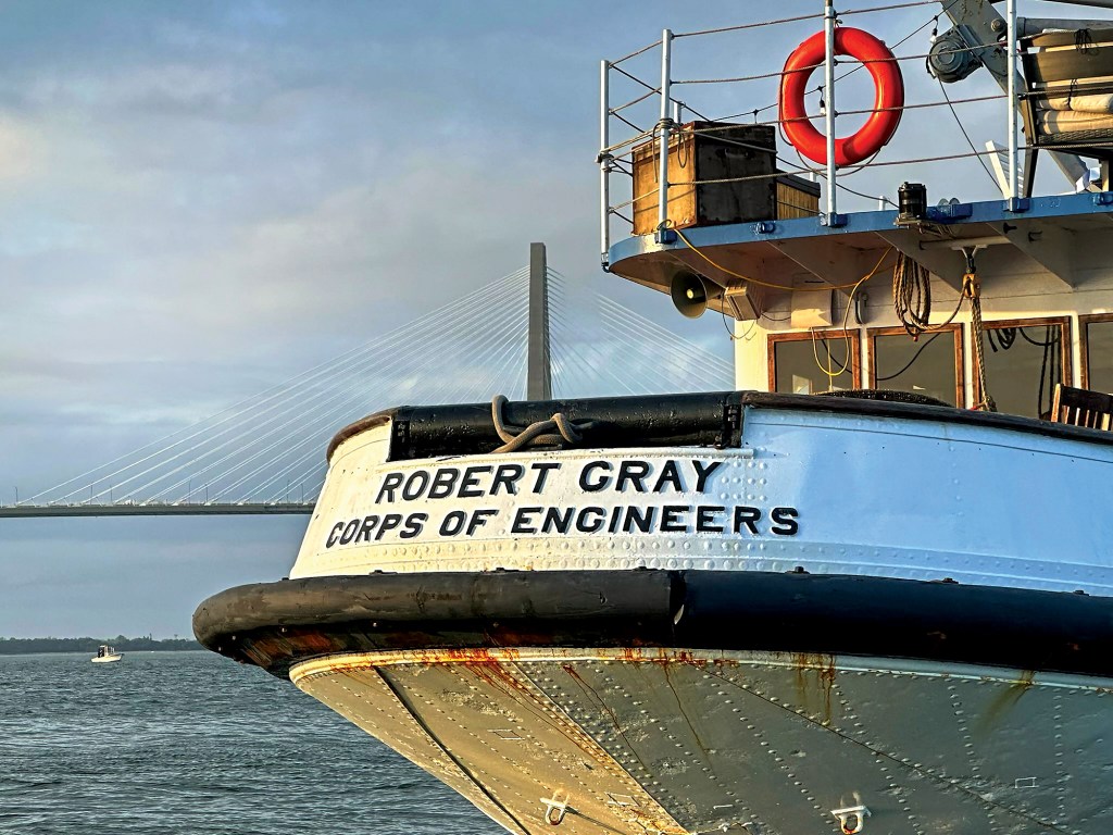 Stern of the historic Robert Gray ship showing Corps of Engineers lettering with Charleston bridge in the background.
