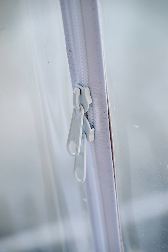 The image shows white double zipper sliders (labeled YKK) installed on a heavy-duty zipper track sewn into clear plastic vinyl paneling, commonly used for marine enclosures, boat covers, or outdoor weather-resistant curtains.