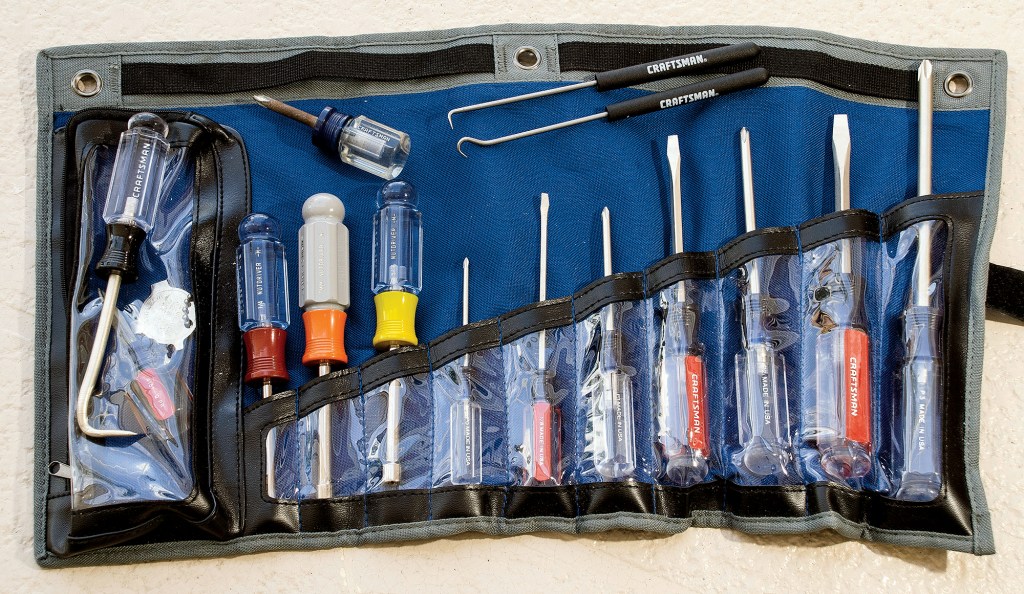 Fabric tool roll pouch containing various screwdrivers, nut drivers, offset drivers, and cotter pin pullers for boat maintenance.