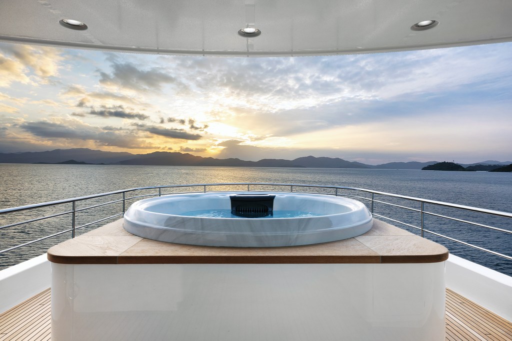 Flybridge jacuzzi hot tub on the upper deck of the Nordhavn 100 overlooking scenic mountains at sunset.