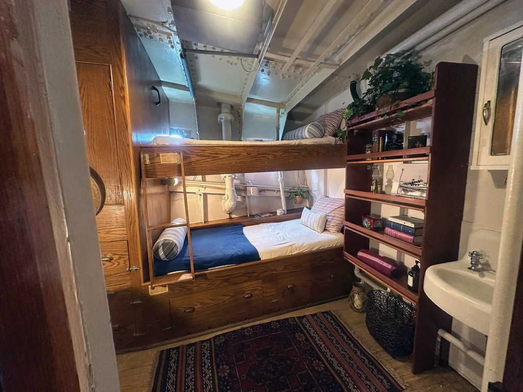 Restored stateroom featuring built-in wooden bunk beds and shelving aboard the historic Robert Gray ship.