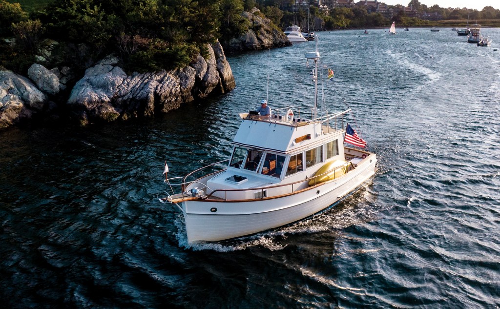 Aerial photograph of Onne van der Wal helming his restored Grand Banks 32 trawler Snow Goose along a rocky coastline.