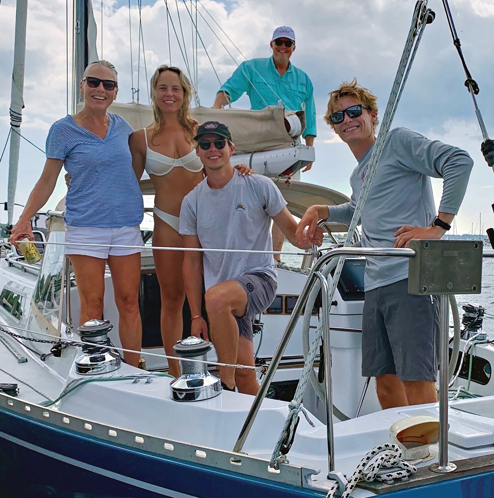 Photographer Onne van der Wal and his wife Tenley posing on deck with family and crew aboard a sailboat.