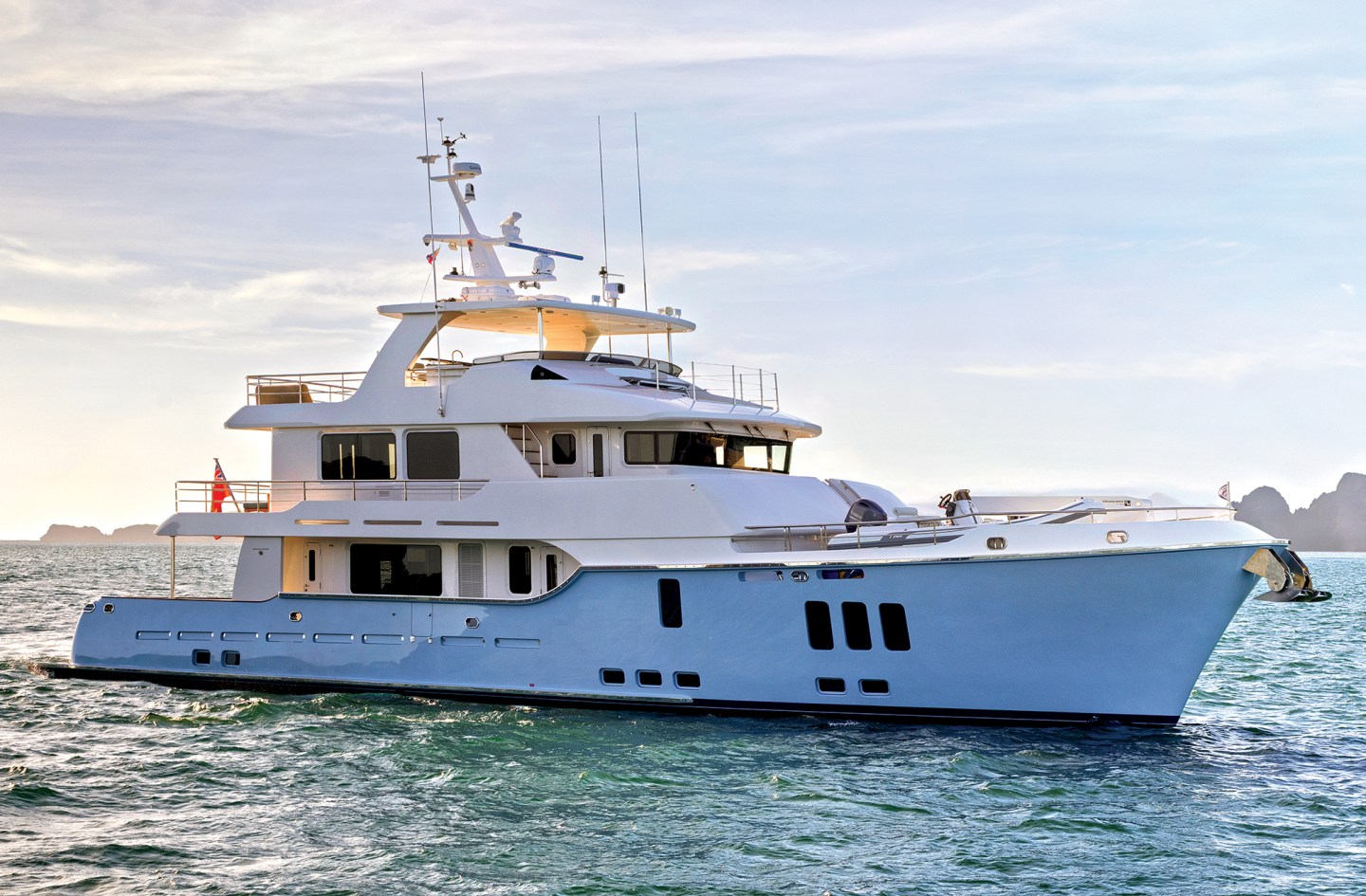 Profile view of a light blue Nordhavn 100 expedition yacht underway on open water.