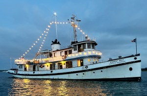 feat_Robert_Gray The historic Robert Gray ship illuminated with string lights on the water at dusk.