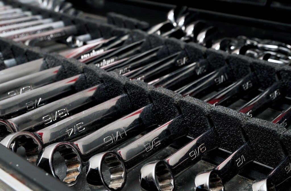 Organized set of chrome combination wrenches in foam storage tray inside a boat toolbox.
