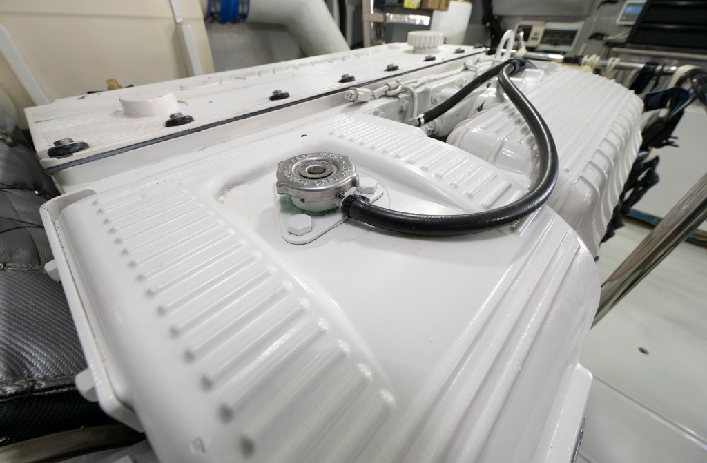 Close-up of a white marine diesel engine heat exchanger with a metal cap during routine preventive maintenance.