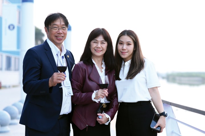 Selene Yachts founder Howard Chen holding a wine glass alongside two women at the shipyard expansion event.