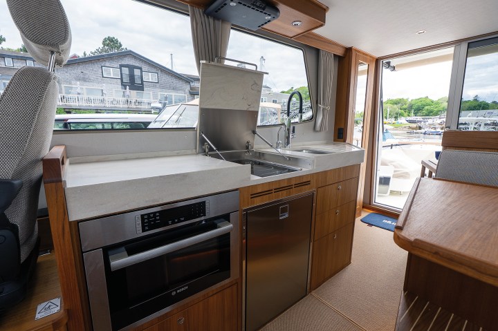 The raised galley of a Targa 41 fitted with light countertops, a stainless steel Bosch microwave oven, under-counter refrigeration, and hidden stovetop burners.