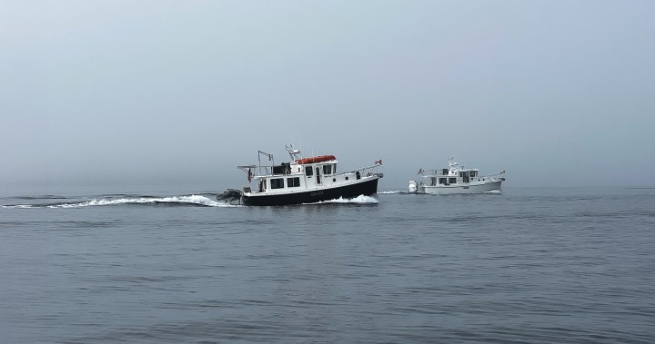 Two tugboat-style powerboats cruising in formation through dense coastal fog on Malaspina Strait.
