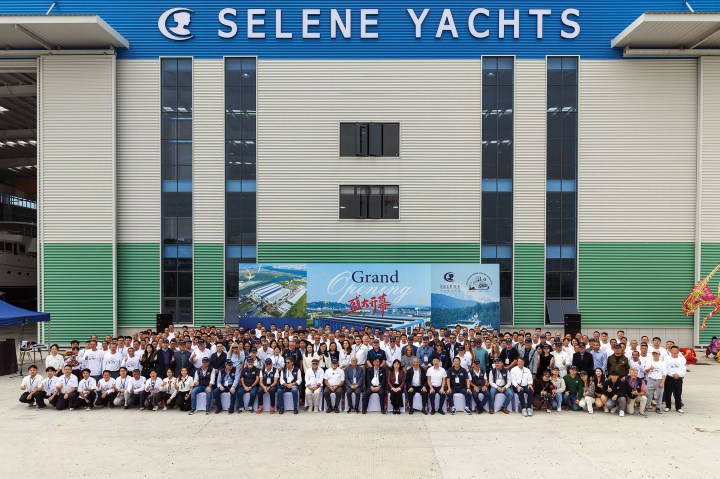 A large group of hundreds of attendees, employees, and dealers posing for a photo outside the newly expanded Selene Yachts shipyard building during the grand opening event.