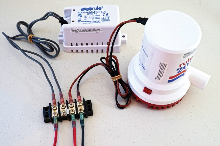 A white Rule-A-Matic Plus float switch and a Rule bilge pump wired into a four-position screw terminal strip with marine crimp connectors.